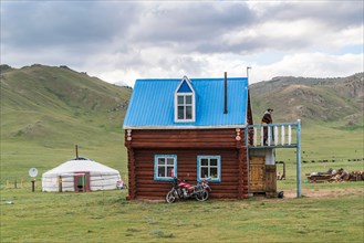 Mongolian man on the terrace of his wooden house. Tariat district, North Hangay province, Mongolia.