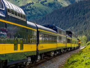 Snow capped mountains in background of Alaska Railroad’s Coastal Classic train from Anchorage to Seward Alaska