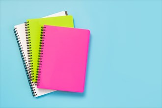 Colorful girlish school supplies, notebooks and pens on punchy blue. Top view, flat lay. Copy space.