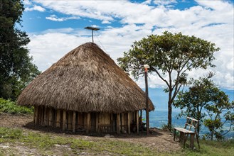 Solar panel and electric light becomes part of grass-topped hut of native Dani people. Wamena, Papua, Indonesia.