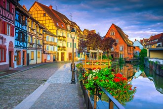 Famous summer travel destination, stunning colorful traditional houses and paved touristic street decorated with flowers at sunrise, Colmar, France, E