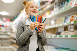 School girl holds markers, stationery store