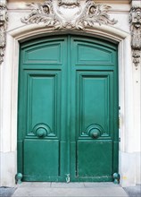Old fashioned front door entrance, white facade and green door, Paris, France