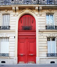 Old fashioned front door entrance, white facade and red door, Paris, France
