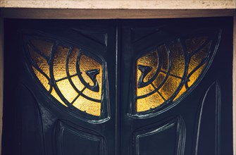 Close up view of black antique doors with ornamental window in Paris