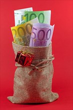 Banknotes, Christmas money in a jute bag against a red background