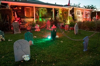 Front lawn decorated as a spooky cemetery for Halloween with tombstones and skeletons