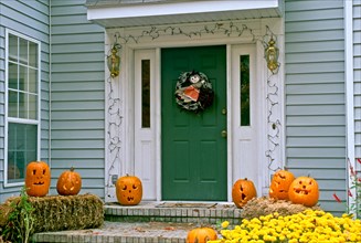 front porch decorated with carved pumpkins and witch wreath for Halloween, Missouri USA