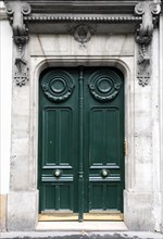 Dark green wooden door in old building facade. Paris, France