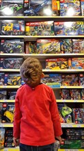 little boy admiring a plaything-shelf with LEGO packings