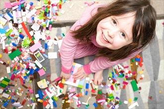 Young smiling girl looking at camera playing with lego
