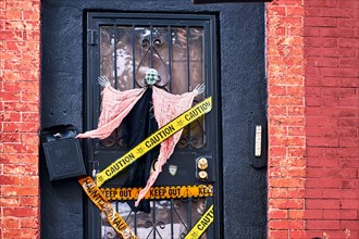 Halloween decorations including a witch and decorative police stripes on the front door of a house in Brooklyn, New York, USA.