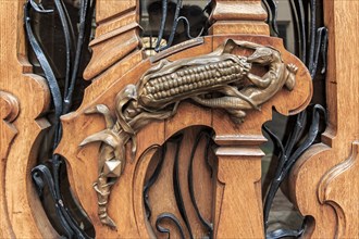 Ornate art nouveau wooden door detail with organic motif and a bronze figurine of a lizard eating an ear of corn for a door handle in Paris, France