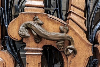 Ornate art nouveau wooden door detail with organic motif and a bronze figurine of a lizard for a door handle in Paris, France