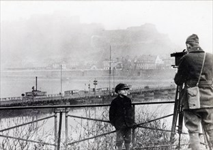 A movie man of the U.S. Sig. Corps, a member of the first American unit to enter the Coblenz with the 4th Div., filming panorama of the Rhine, with the fortress of Ehrenbreitstein in the background ca...