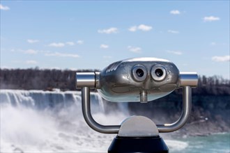 Tourism coin operated binoculars with Niagara Falls in the background. Concept of reopening the US Canada border.