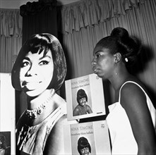 Singer Nina Simone stands besides a poster advertising on of her records at a press reception held at Philips record company building at Stanhope PlaceJuly 1965