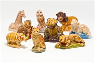 Close up of a collection of Wade Whimsies, small porcelain animal figurines popular with collectors since the 1950s, against a white background.