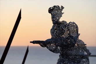 Life size sculptural figure in the D-Day 75 Garden in Arromanches-les-Bains, France at Sunset.  The installation was first created by John Everiss for
