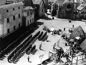 On Set candid filming Parade of German Soldiers on Universal Studios Lot with part of Paris set from Lon Chaney's Hunchback of Notre Dame (1923) at top right and Native Huts from The Invisible Ray (19...