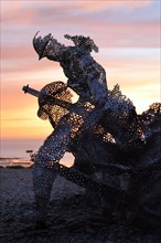 Life size sculptural figure in the D-Day 75 Garden in Arromanches-les-Bains, France at Sunset. The installation was first created by John Everiss for