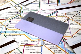 A subway pass card and subway tickets on the top of a Paris Metro map. The allows to travel in all Grand Paris during 2 weeks or one month while subwa