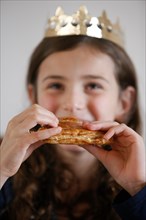 Girl eating Galette des rois, French pastry eaten on Epiphany