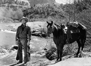 1948, Film Title: BLOOD ON THE MOON, Director: ROBERT WISE, Studio: RKO, Pictured: CLOTHING, HORSE, ROBERT MITCHUM, WESTERN, COWBOY, NATURE, RIVER, CHAPS, COWBOY HAT, NECK SCARF, DRIFTER, NOMAD. (Cred...