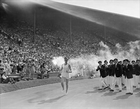 Olympic Games, London, 1948. British athlete John Mark brings the olympic torch around the track and eventually lights the Olympic Flame.