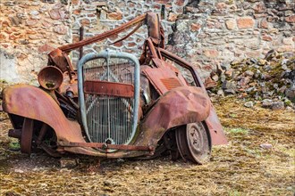 Europe, France, Haute-Vienne, Oradour-sur-Glane. Sept. 5, 2019. Rusted car in the ruins of the martyr village of Oradour-sur-Glane.