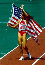 Florence Griffith Joyner (USA) celebrates with the American Flag after winning the gold medal in the Women's 100m Final at the 1988 Olympic Summer Games.
