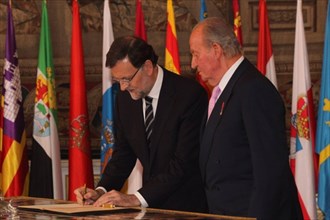 Spain s Prime Minister Mariano Rajoy (L), with the King Juan Carlos I de Borbon of Spain aside, signs the law on the king s abdication at the Royal Palace of Madrid in Madrid, June 18, 2014. The King ...