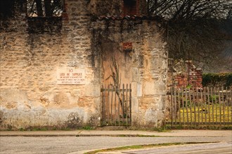 ORADOUR SUR GLANE, FRANCE - December 03, 2017 : on the wall of the remains of a house, a stone panel where it is written in French - here place of tor