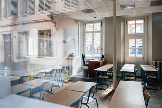 View from the street of large school classroom with empty seats - reflections of city in the window