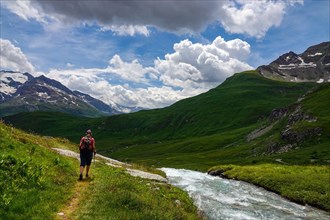 Female hiker with red rucksack in the La Lenta valley, under the Col d'Iseran, Vanoise National Park, France