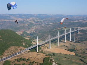 AIR-TO-AIR VIEW. Paramotors flying in the vicinity of the Millau Viaduct, the world's tallest bridge as of 2020. Millau, Tarn Valley, Aveyron, France