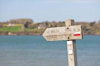 The old wooden sign shows coastal hikers the way to Saint Cast le Guildo along the GR34 long-distance hiking trail between St. Malo and Cap Frehel, Brittany, France