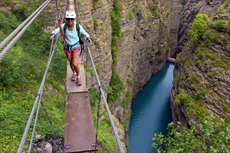 man on narrow rope bridge, via ferrata du Barrage du Sautet, France, Isere