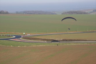 Aerial photograph of a paramotor (motorized paraglider) flying over a roundabout in soindres fields, Yvelines department (78200), Ile-de-France region