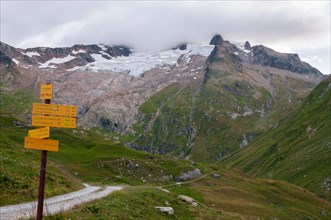 Hiking signposts on the GR Tour du Mont-Blanc trail near the refuge des Mottets with view of the glacier des Glaciers, Chapieux Valley, Savoie (73), A