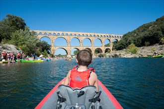 A family kayaks down a river on inflatable kayaks in Southern France