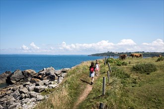 A young family walking along the GR34 coastal path between Primel Tregastel and St Jean du Doigt on a beautiful summer day in Britanny, France.