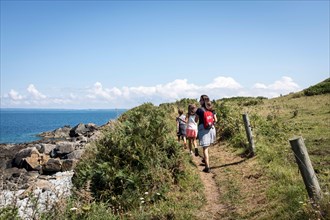 A small family walking along the GR34 coastal path between Primel Tregastel and St Jean du Doigt on a beautiful summer day in Britanny, France.