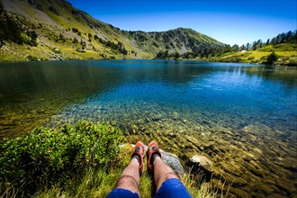 Lake and legs during mountain hiking at Pyrenean mountain