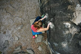 young caucasian woman rock climbing in forest of Fontainebleau