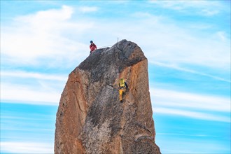 Climbers climbing a large rock on the summit of Aiguille du Midi in Mont Blanc, France