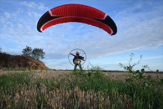 Paramotor pilot reverse launching, France, Brittany, Erquy