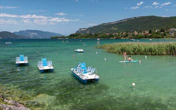 Nautical activities on the clear blue water of Lake Bourget surrounded by the Jura Mountains in the department of Savoie, France.