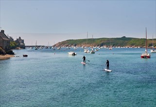 Two people perform paddle boarding in marina in Finister, France