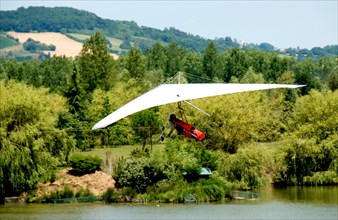 Hang glider taking off by a lake at an airshow in France.